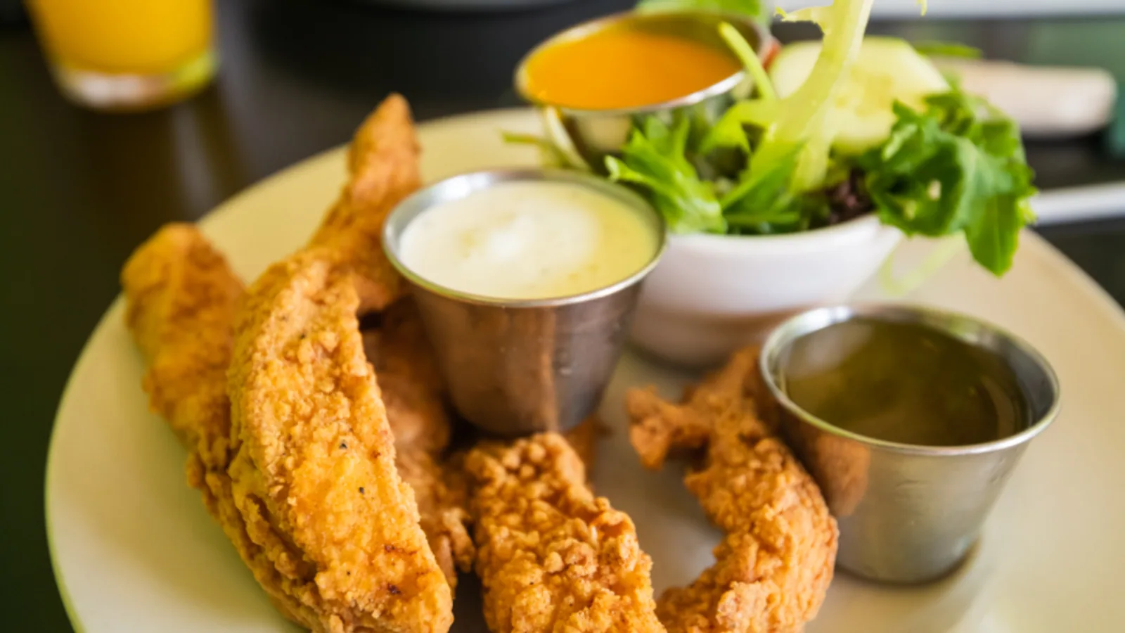 Fried chicken pieces served with two dipping sauces and salad