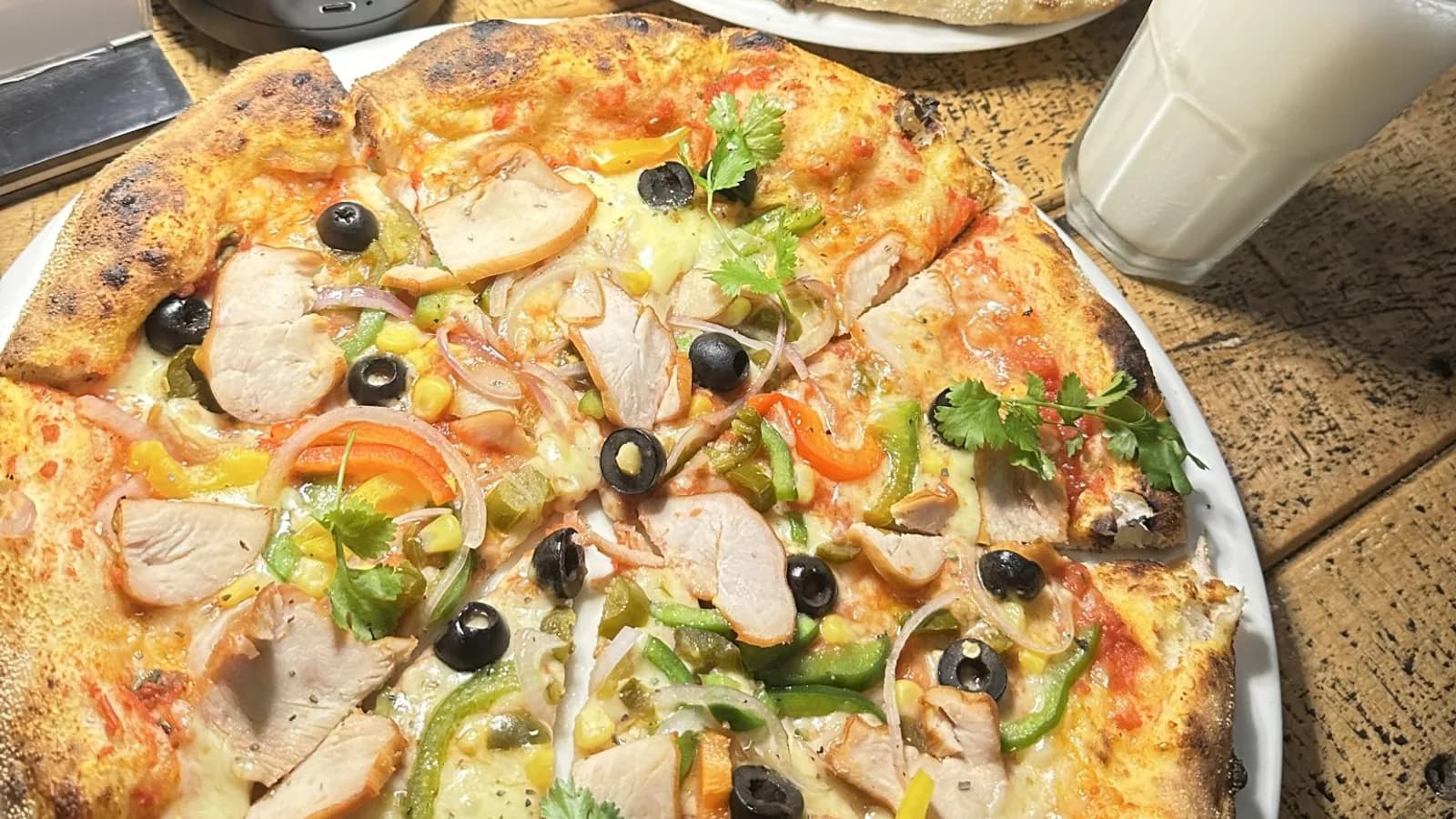 Two topped pizzas side by side on a metal tray
